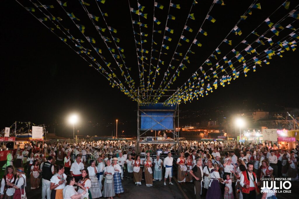 Crowd in Canarian traditional dress beneath bunting at the July 2026 Baile de Magos