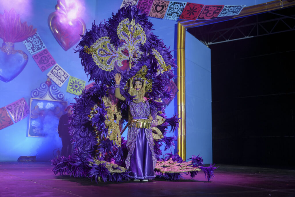 A young participant in a purple and gold feathered costume at the Puerto de la Cruz children’s Carnival gala
