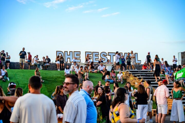 Festivalgoers socialising beside the Phe Festival sign in Puerto de la Cruz