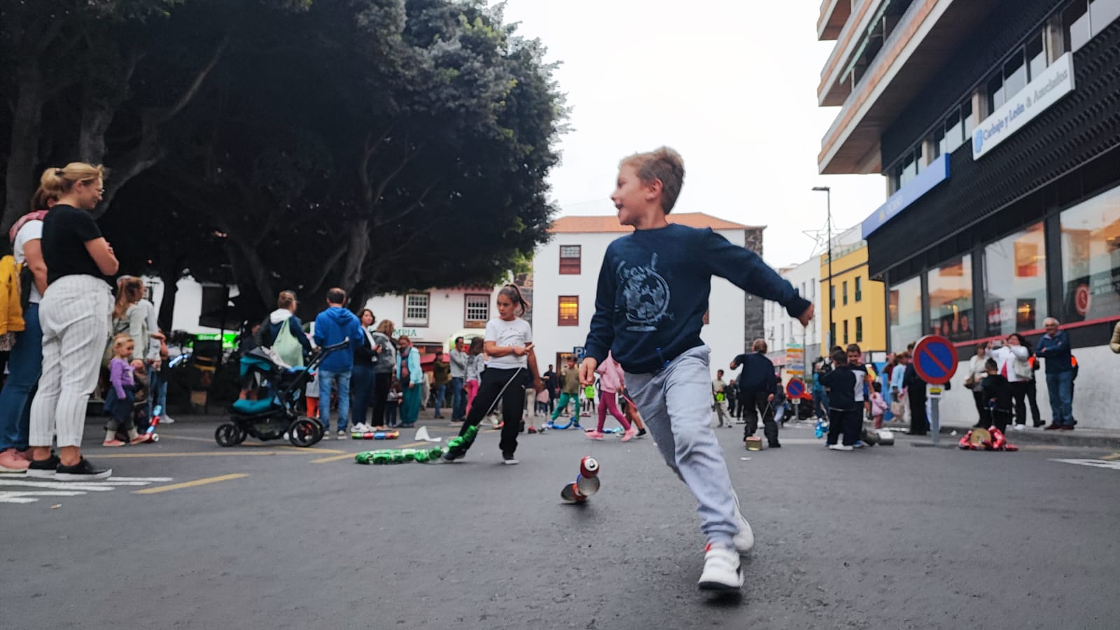 A child running a tin-can cacharro in Puerto de la Cruz during the 2022 celebration. Photo: Ayuntamiento de Puerto de la Cruz. A child pulling a tin-can cacharro along a street beside Plaza del Charco during San Andrés in 2022