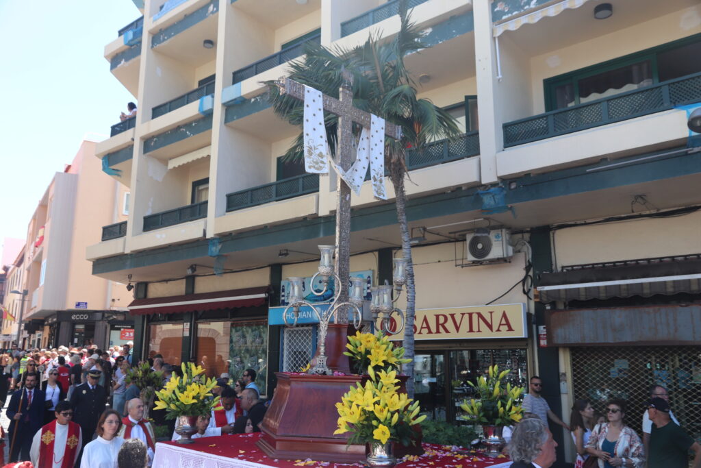 Santa Cruz on the town-centre procession route in May 2026 Santa Cruz with white cloth and yellow flowers carried through a Puerto de la Cruz street in May 2026