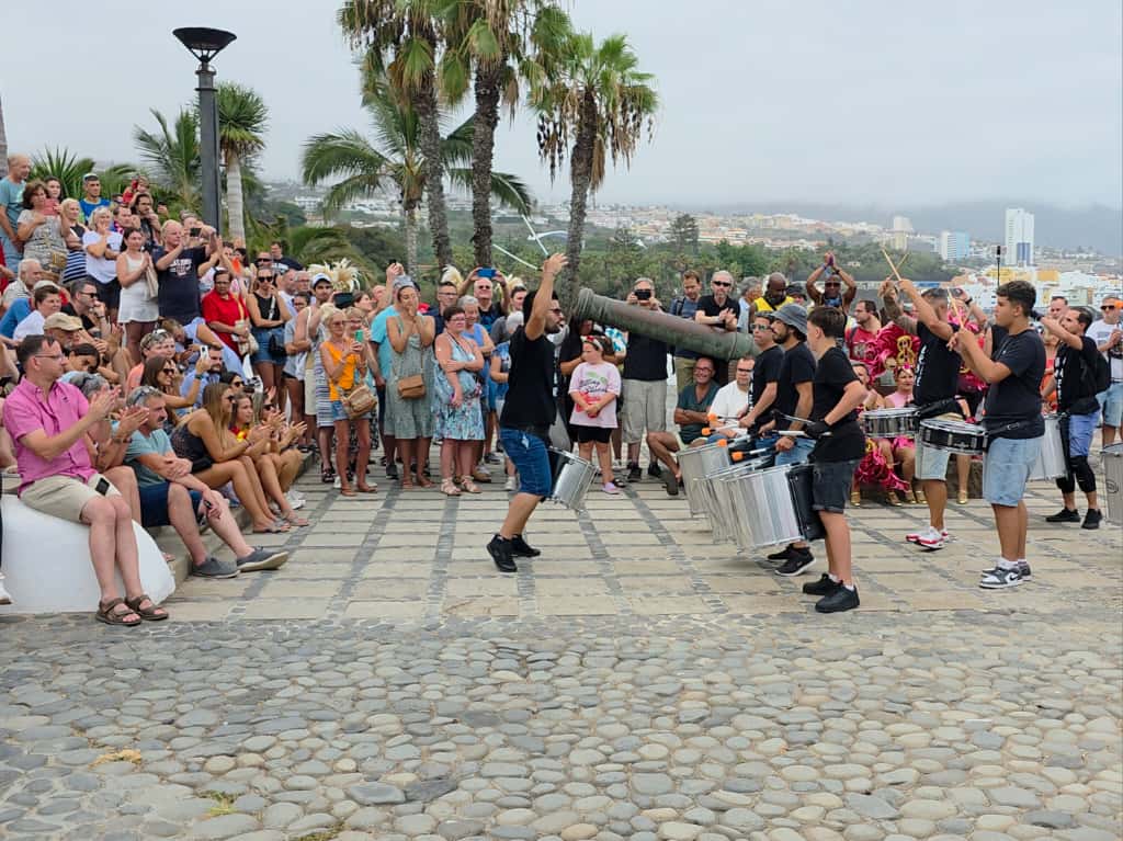 Percussion performers playing for a crowd on a Puerto de la Cruz seafront promenade during Summer Carnival 2025