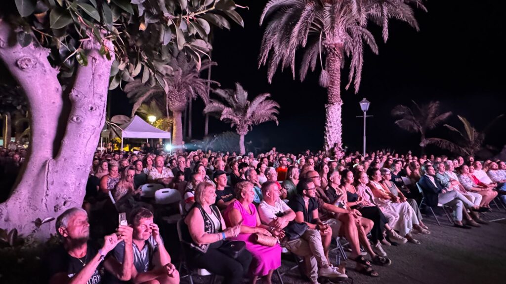 Audience seated under palm trees for an outdoor Summer Carnival performance in Puerto de la Cruz in 2025