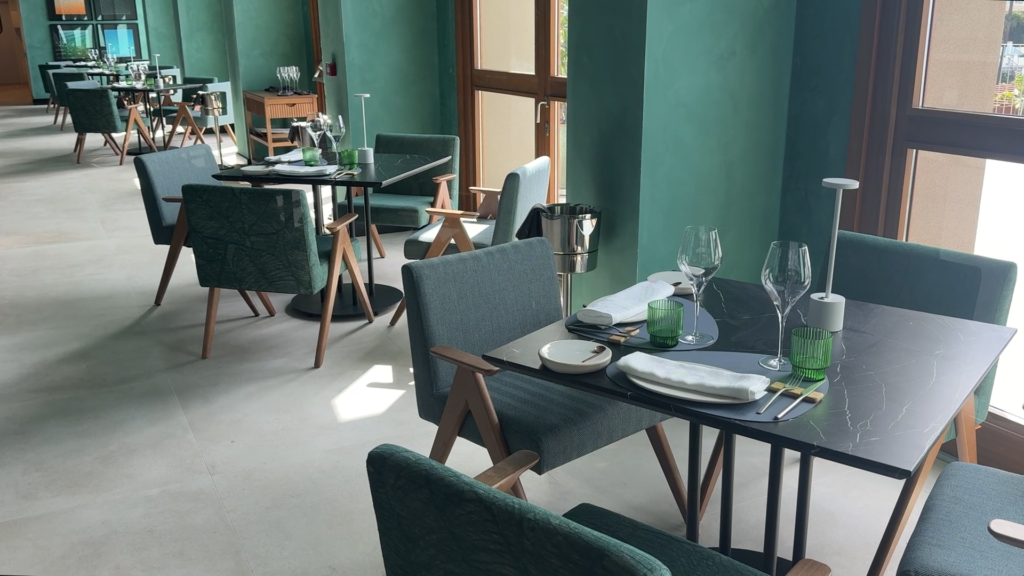 Tables set with plates and wine glasses in a green dining room at Gran Hotel Taoro