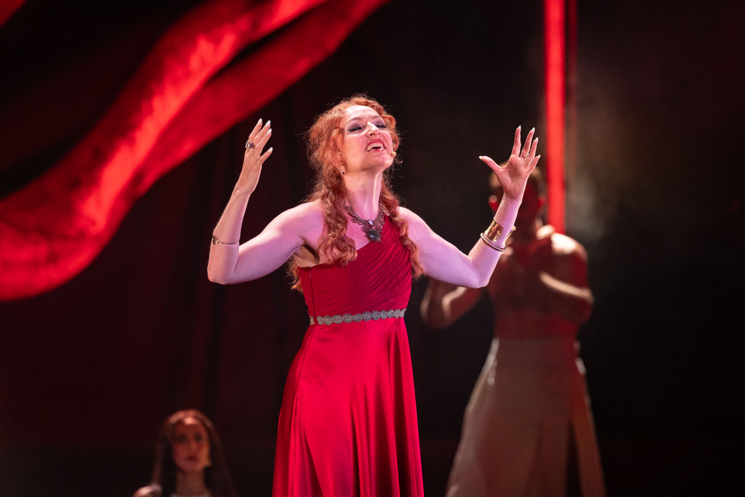 Theatre performer in a red dress on stage at Veranos del Taoro